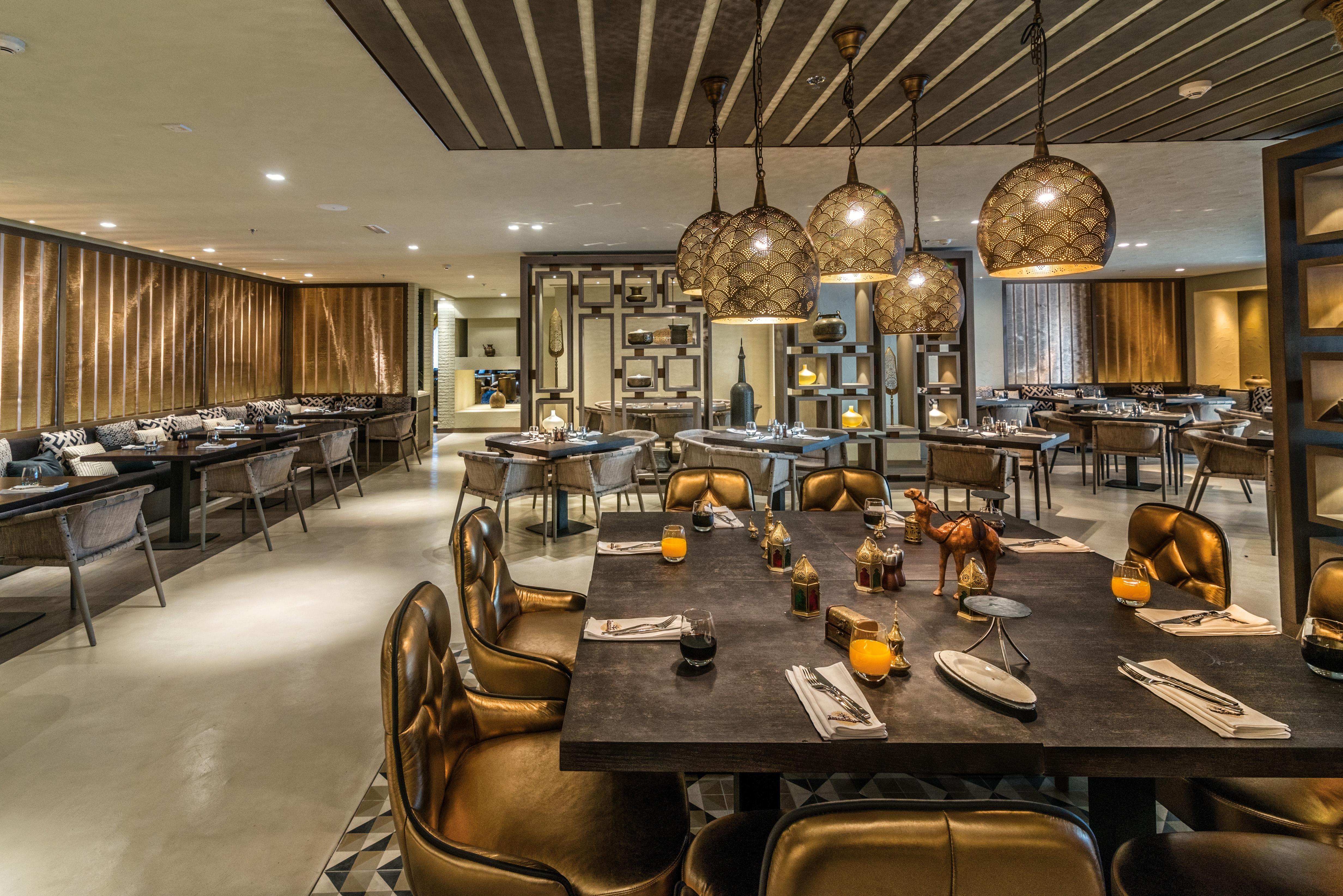 Radisson Blu Hotel, Dubai Deira Creek Esterno foto The photo shows a modern restaurant interior. The space is elegantly designed with wooden panels and contemporary lighting fixtures, including decorative pendant lights hanging from the ceiling. There are several dining tables arranged throughout the