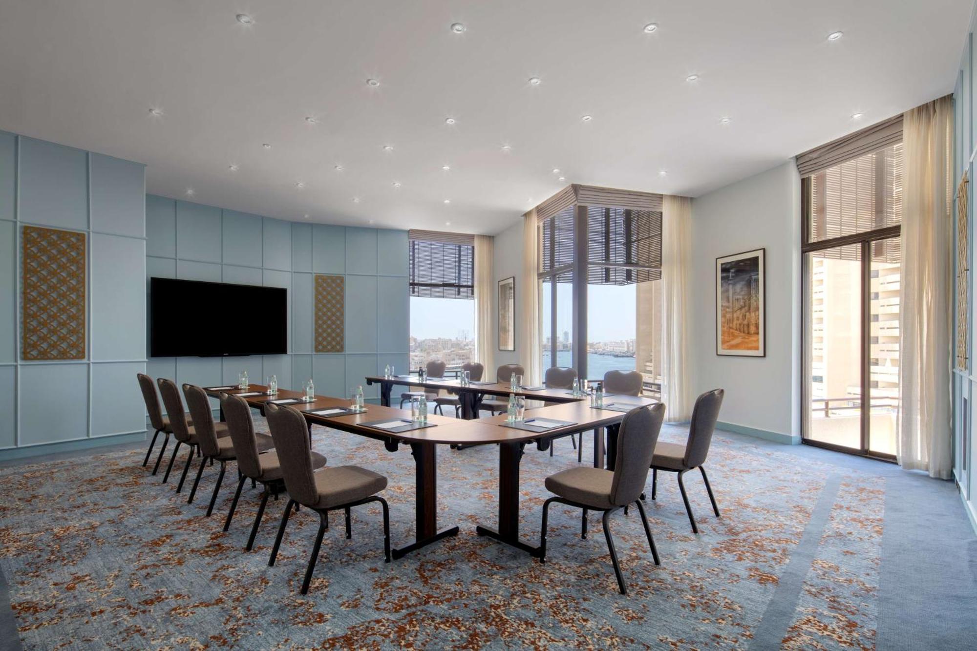 Radisson Blu Hotel, Dubai Deira Creek Esterno foto The photo shows a conference room designed for meetings. It features a long table surrounded by several chairs, with the layout suggesting a professional setting. The room has large windows that allow natural light to enter and offer a view outside. 