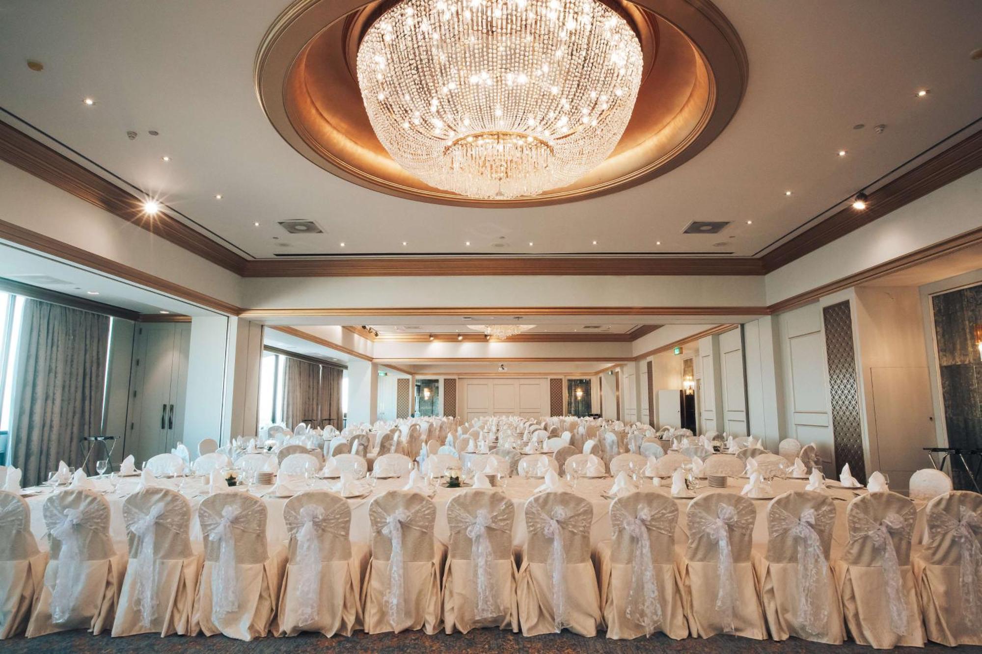 Radisson Blu Hotel, Dubai Deira Creek Esterno foto The photo shows a beautifully decorated banquet room with elegant white tablecloths and chair covers. The layout features rows of tables arranged in a formal setting, likely for an event such as a wedding or banquet. A large, ornate chandelier hangs 