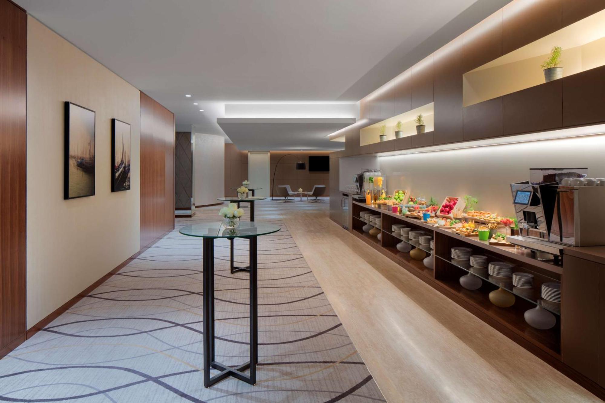 Radisson Blu Hotel, Dubai Deira Creek Esterno foto The photo shows a modern and elegantly designed hallway or lounge area. On one side, there are two artwork pieces hung on the wall, likely featuring abstract designs or landscapes. Opposite this, there's a long, low table or countertop with various f