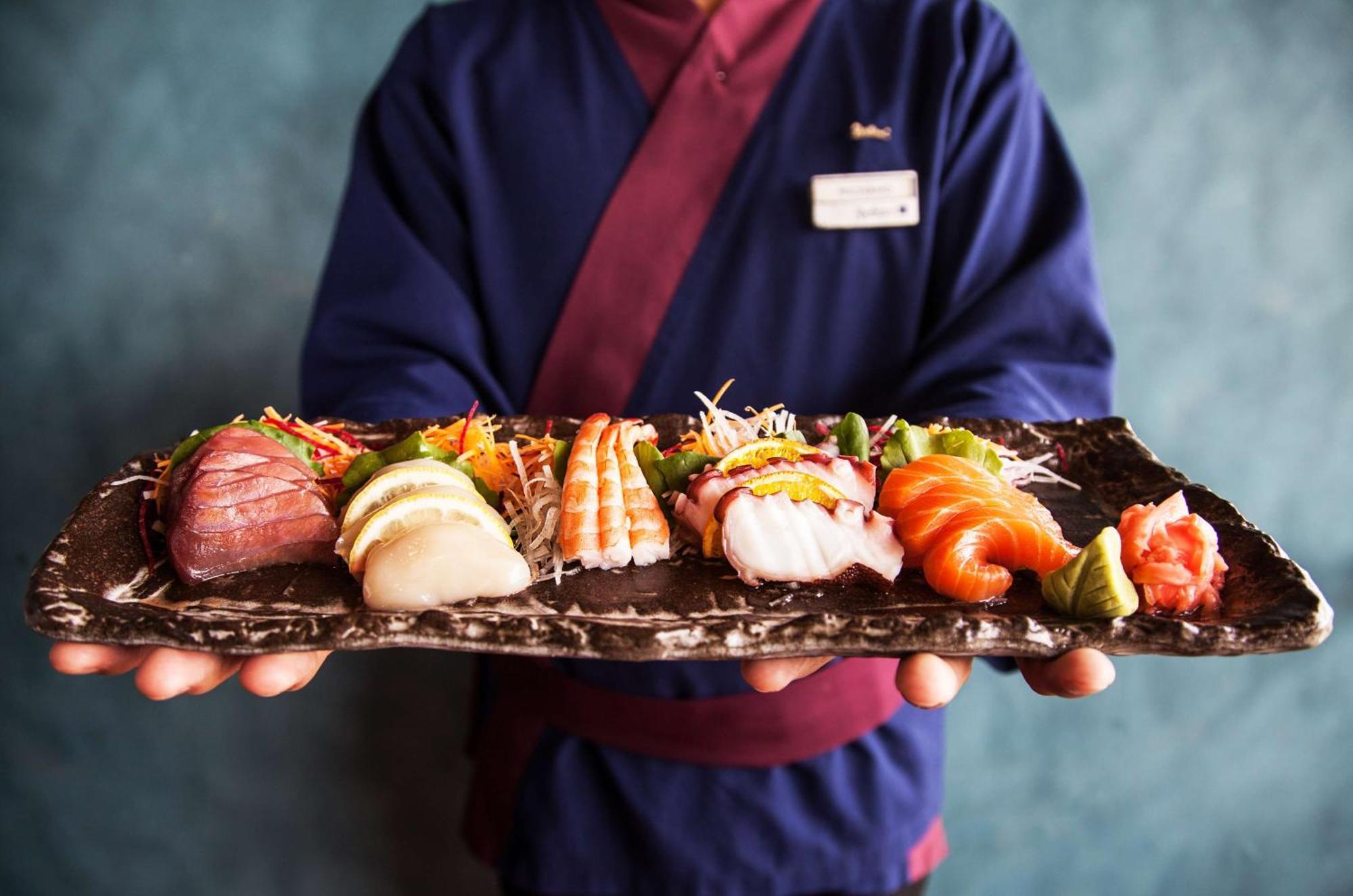Radisson Blu Hotel, Dubai Deira Creek Esterno foto A sushi chef holding a plate of sushi